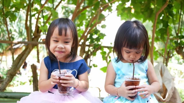 Kleines-asiatisches-Kind-Mädchen-schlürft-ihr-Getränk,-während-sie-ruhe-im-Park-am-Sommertag.-Selektiver-Fokus.
