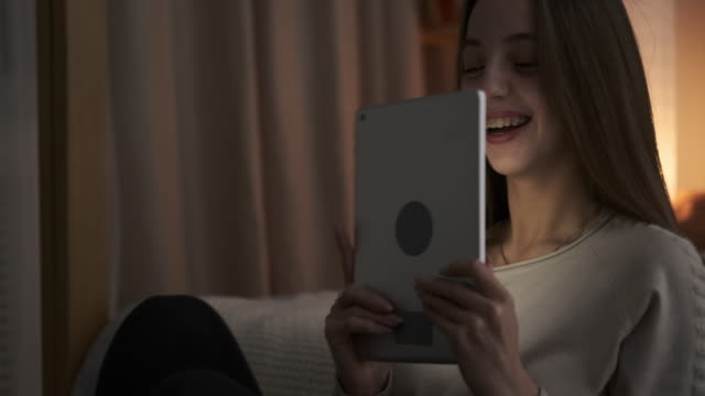 Teen-girl-having-fun-using-digital-tablet-at-night