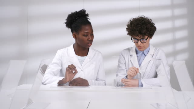 Two-Female-Scientists-Working-on-Futuristic-Touchscreens-Together-in-Lab