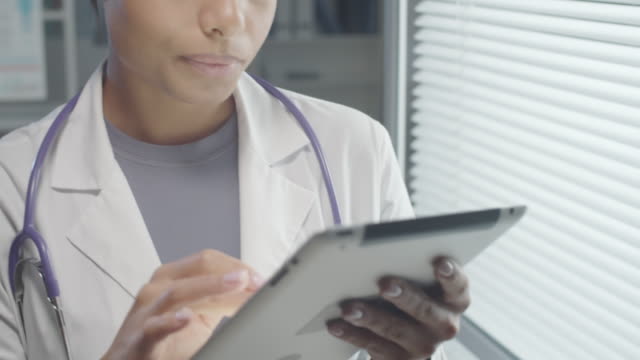 Mixed-Raced-Weibliche-Ärztin-Surfen-im-Internet-auf-digitalen-Tablet