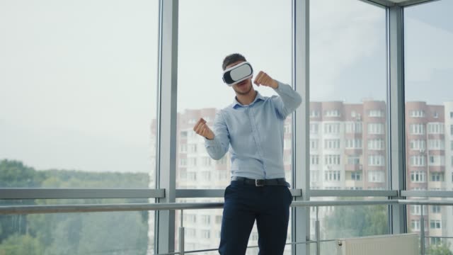 Nahaufnahme-Junger-Mann,-der-an-einem-Schreibtisch-im-Büro-sitzt,-verwendet-Augmented-Reality-Brillen,-um-an-Geschäftsprojekten-in-verschiedenen-Bereichen-zu-arbeiten.-Arbeiten-in-Virtual-Reality