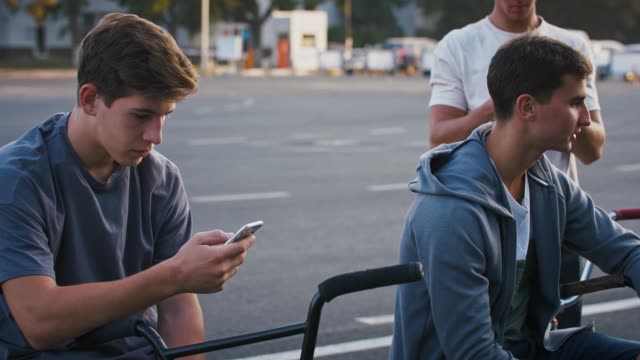Junger-Mann-benutzt-sein-Smartphone,-während-er-sich-nach-dem-Training-mit-Freunden-auf-dem-bmx-Fahrrad-ausruht
