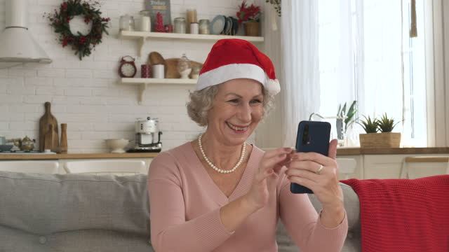 Cheerful-old-woman-in-red-hat-smiles-conducting-video-call