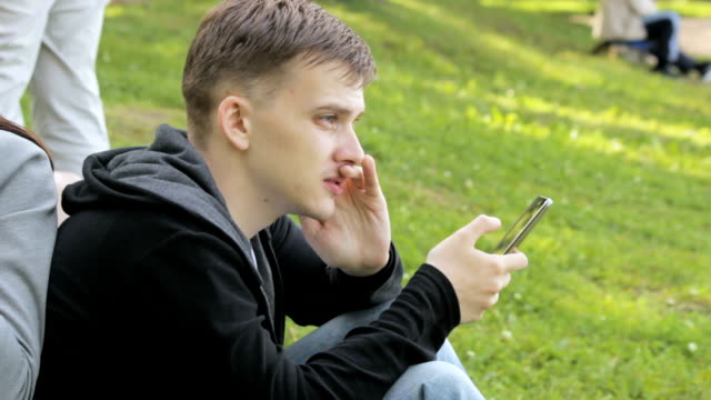 Mann-auf-der-Suche-nach-Informationen-über-ein-Smartphone-im-park