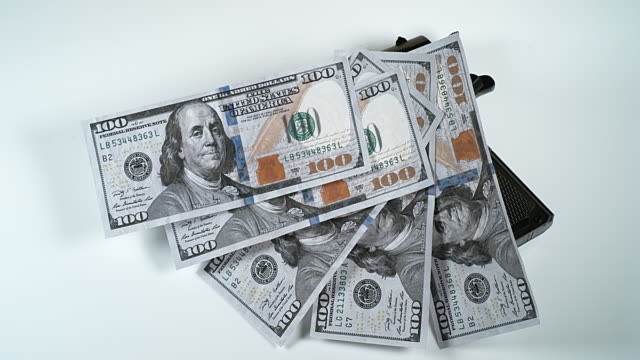 Pistole-und-100-US-Dollar-Banknoten-vor-weißem-Hintergrund,-Slow-Motion-4K
