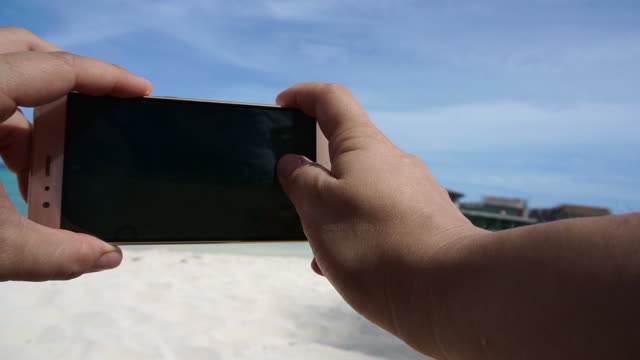 POV-shot-of-a-smart-phone-taking-photo-in-tourist-hand.-Having-fun-at-ocean-vacation