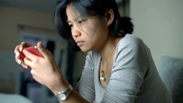 Junge-Thai-Mädchen-mit-Smartphone-im-Wohnzimmer