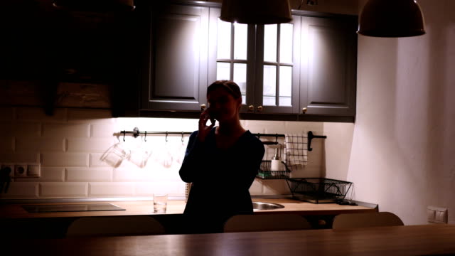 Stehende-Frau-am-Abend-Telefonieren-in-dunklen-Küche