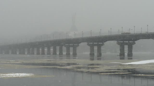 Blick-auf-die-Paton-Brücke-im-Winter.-Schneefall-in-Kiew-in-der-Nähe-des-Dnjepr.