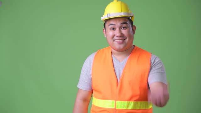 Trabajador-de-la-construcción-del-joven-guapo-asiáticos-con-sobrepeso-sobre-fondo-verde