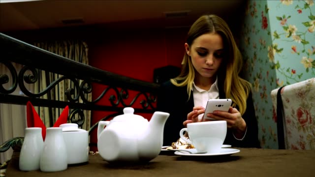 Junges-Mädchen-im-Café-mit-Smartphone-über-eine-Tasse-Tee