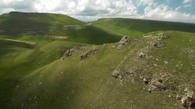 Eine-große-Felsformation-unter-den-grünen-Feldern-herumfliegen.-Russland.-Nord-Kaukasus