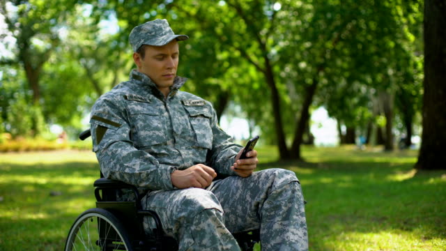 Militares-discapacitados-hombre-desplazamiento-fotos-de-smartphone,-descansar-en-el-parque-de-la-ciudad,-nostalgia