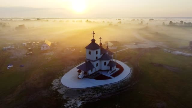 Luftaufnahmen-Video-der-kleinen-Dorfkirche-am-nebligen-Morgen.-Sonnenaufgangszeit.-Kyiv-Region,-Ukraine.-Fliegen-über-den-Fluss-Desna