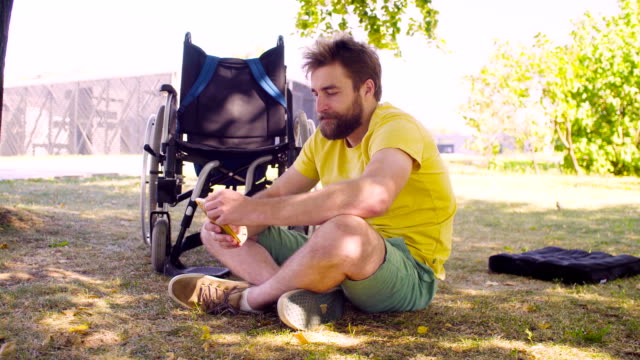Happy-young-disable-man-sitting-on-the-grass-in-the-park