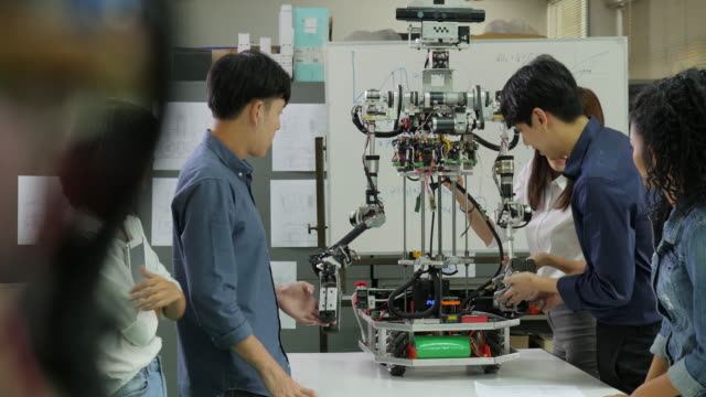 Junge-Elektronik-Ingenieur-Team-gemeinsam-an-der-Konstruktion-des-Roboters-in-der-Werkstatt.-Team-Ingenieur-Inbetriebnahme-für-Roboter-Projekt-zusammen.-Menschen-mit-Technologie-oder-Innovation-Konzept.