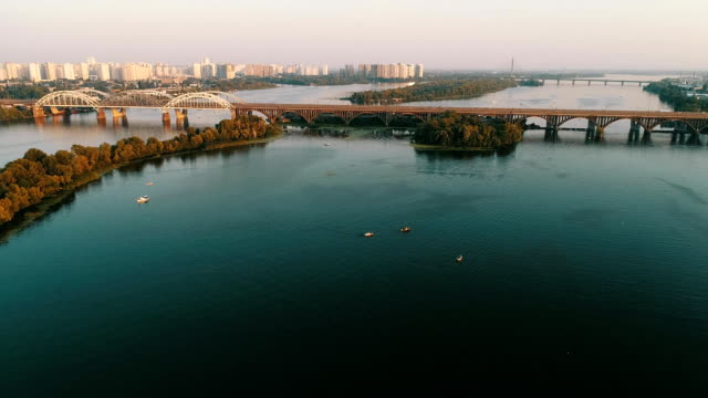 Aerial-view-of-the-Kyiv-city,-Ukraine.-Dnieper-river-with-bridges.-Darnitskiy-bridge.-Poznyaki-district-in-the-background