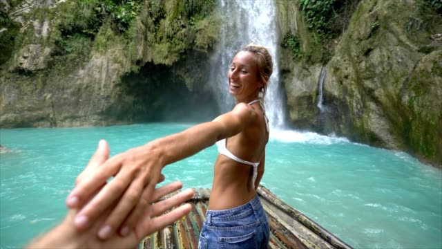 Follow-me-to-concept-young-woman-leading-boyfriend-to-amazing-waterfall,-shot-in-Cebu-Island,-Visayas-Islands,-Philippines.-Idyllic-tropical-travel-journey-vacations-concept.-Slow-motion-video