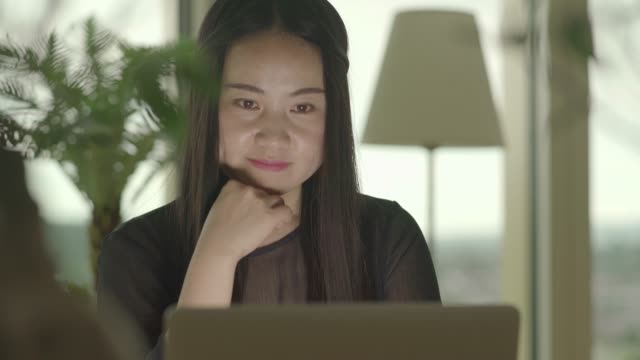 Mujer-asiática-joven-escribiendo-en-el-ordenador-portátil-mientras-escucha-música-por-los-auriculares
