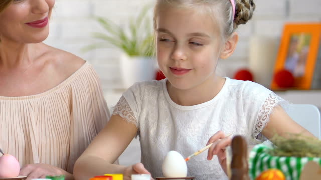 Niedliche-Tochter-küssen-Mutter-auf-Wange-Dekoration-Ostern-Eier,-Fest-vorbereiten