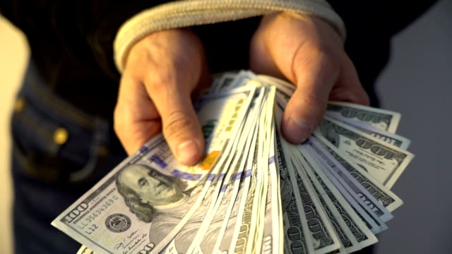 male-hand-bound-with-the-rope-holding-pile-of-money-american-dollar-bank-notes,-financial-rectrictions-concept