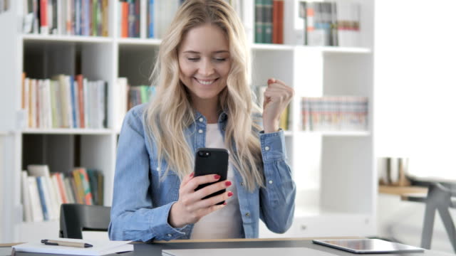 Female-Casual-Designer-Excited-for-Success-while-Using-Smartphone