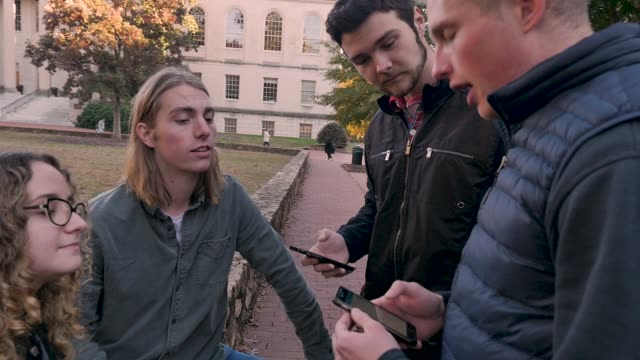 Männliche-College-Student-über-seine-mobile-App-zu-seinen-Klassenkameraden-draußen