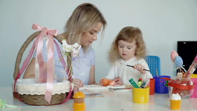 Mutter-und-ihre-kleine-Tochter-malen-Ostereier
