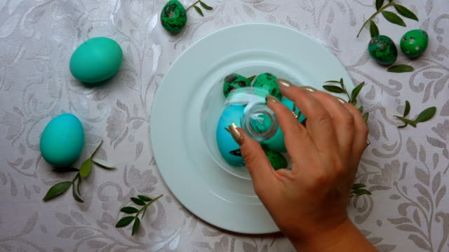 Hand-removes-a-glass-dome-from-a-plate-with-green-easter-eggs