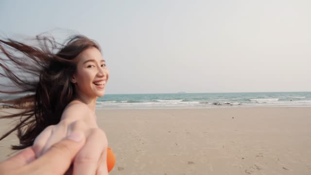 Asiatische-schöne-Frau-hält-ihre-Freundin-Hand-und-läuft-zum-Strand.-Sommer-und-Reisekonzept.