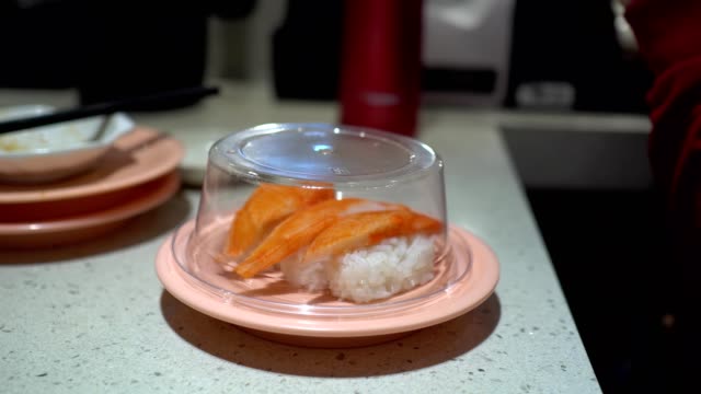 Das-kleine-Mädchen-isst-Sushi-in-einem-japanischen-Restaurant.-Das-kleine-Mädchen-trägt-ein-Hörgerät.