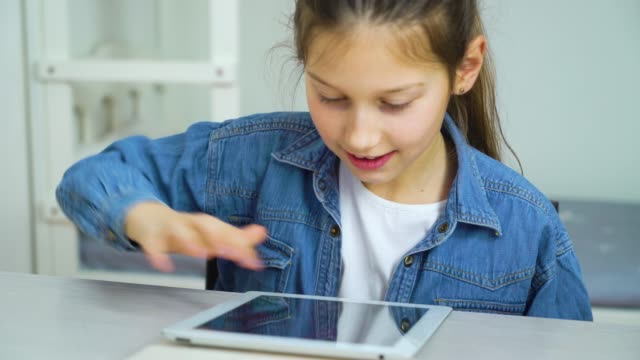 Glückliches-kleines-Mädchen-berühren-Bildschirm-des-Tablets-beim-Spielen-online