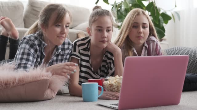 Teenager-Girls,-die-Medieninhalte-auf-dem-Laptop-beobachten,-während-sie-Snacks-zu-Hause-haben