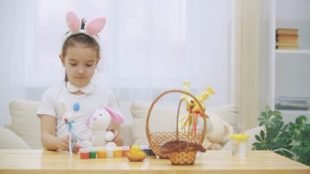 Little-cute-and-adorable-girl-is-smiling-and-playing-with-Easter-bunnies-in-her-hands.-Concept-Easter-holiday.