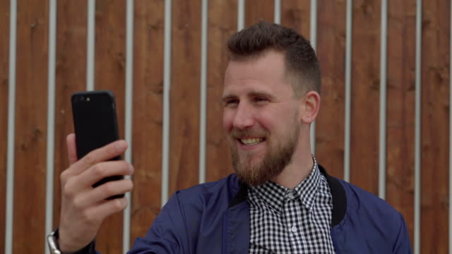 Cheerful-handsome-guy-is-talking-by-mobile-phone-using-video-call