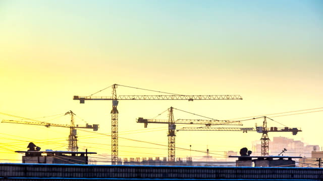 silhouette-of-cranes-working-on-construction-site-on-sunset-sky-background.