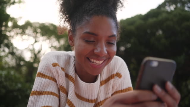 Low-Winkel-Ansicht-einer-afrikanischen-jungen-Frau-im-Freien-mit-dem-Smartphone