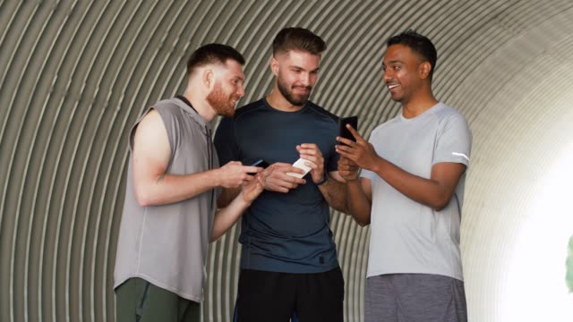 sportliche-Männer-oder-Freunde-mit-Smartphones-im-Freien