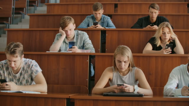 Multi-Ethnische-Gruppe-von-Studenten-mit-Smartphones-während-der-Vorlesung.-Junge-Menschen,-die-soziale-Medien-während-des-Studiums-an-der-Universität-nutzen.