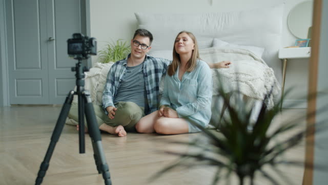 Pareja-casada-bloggers-grabando-vídeo-en-el-dormitorio-hablando-mostrando-pulgars-hacia-arriba