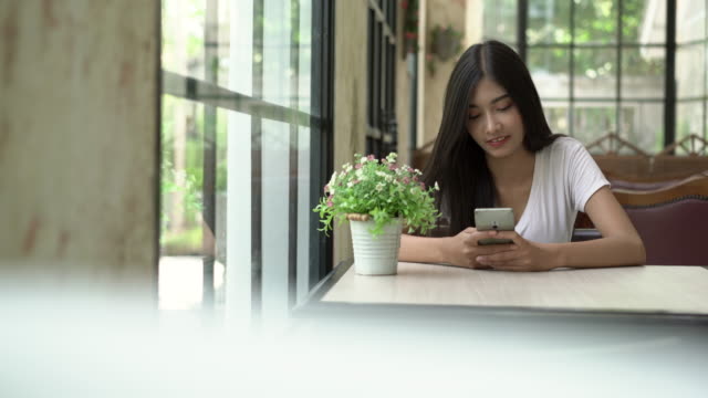 Schöne-asiatische-Frau-mit-Smartphone-im-Café.-Sie-benutzte-Smartphone,-um-Social-Media-mit-lächelnund-glücklich-zu-überprüfen.-Fokusaufnahme-auswählen