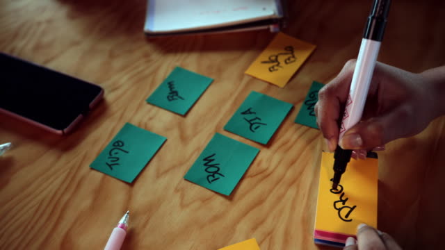 De-cerca-negro-joven-mujer-escribiendo-en-notas-pegajosas-de-colores