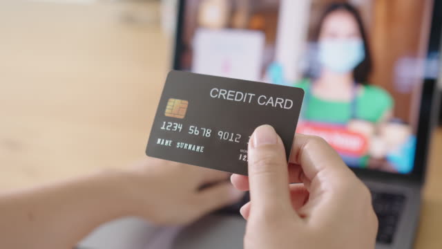 Close-up-consumer-woman's-hand-holding-credit-card-making-e-bank-online-payment-for-purchase-in-online-website-store-with-laptop-computer.-Ecommerce-website-payments.-new-normal-digital-lifestyle