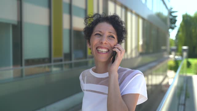 Zoom-in-Nahaufnahme-von-lächelnden-Unternehmerin-sprechen-auf-Handy-außerhalb-Büro-in-der-Stadt