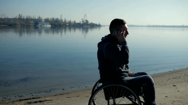 Male-in-wheelchair-speaking-on-mobile-phone,-physically-disabled-man-sits-in-wheelchair