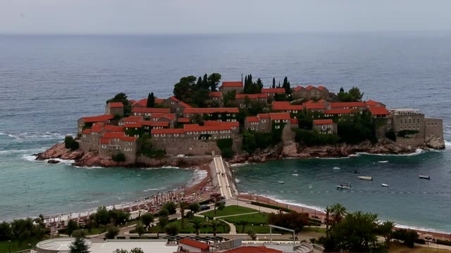 Sveti-Stefan-island-Montenegro.-Zoom-out-shot.-Saint-Stephen-Montenegro-Adriatic-coast-line-pink-sand-beaches-boat-on-sea-blue-water.-Resort-for-Rich-mans.-Aerial-view-to-island-isthmus.