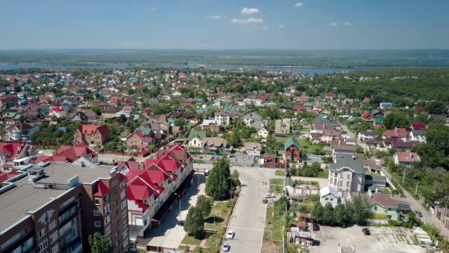 big-city-near-river,-aerial-view,-multicolor-roof-of-houses,-sunny-summer-day,-clear-blue-sky-with-small-clouds