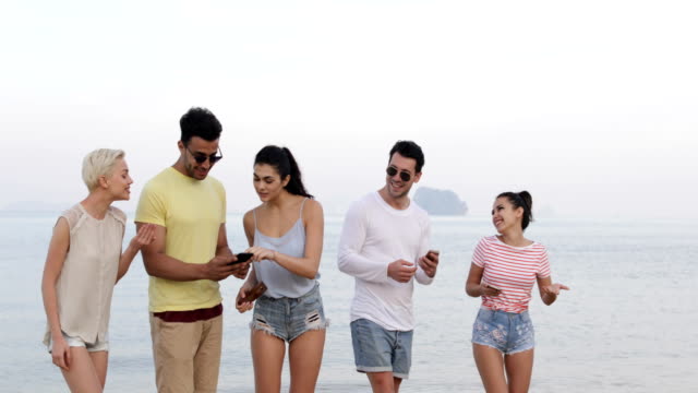 Menschen-zu-Fuß-am-Strand,-im-Gespräch-mit-Smart-Phones,-junge-Touristen-Zellgruppe-Networking-Online-lachen