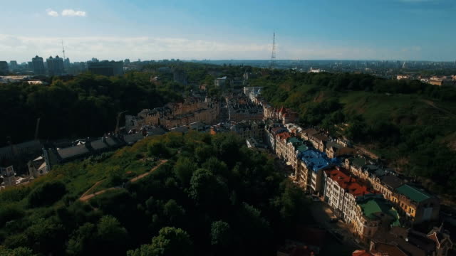 Drone-Camera-Moves-under-Roofs-of-Buildings-on-the-Old-Narrow-European-Streets-with-Colorful-Houses-and-Pedestrians-at-Sunset-4K