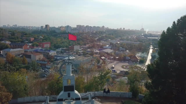 Red-waving-flag-and-beautiful-city-landscape,-top-view.-Clip.-Aerial-view-on-Russial-city-with-red-waving-flag